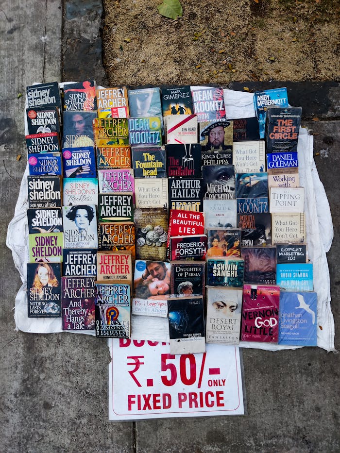 Collection of paperback books displayed on the street with a fixed price sign.